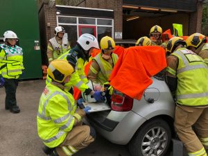 Firefighters work with trainee ambulance technicians on staged collision