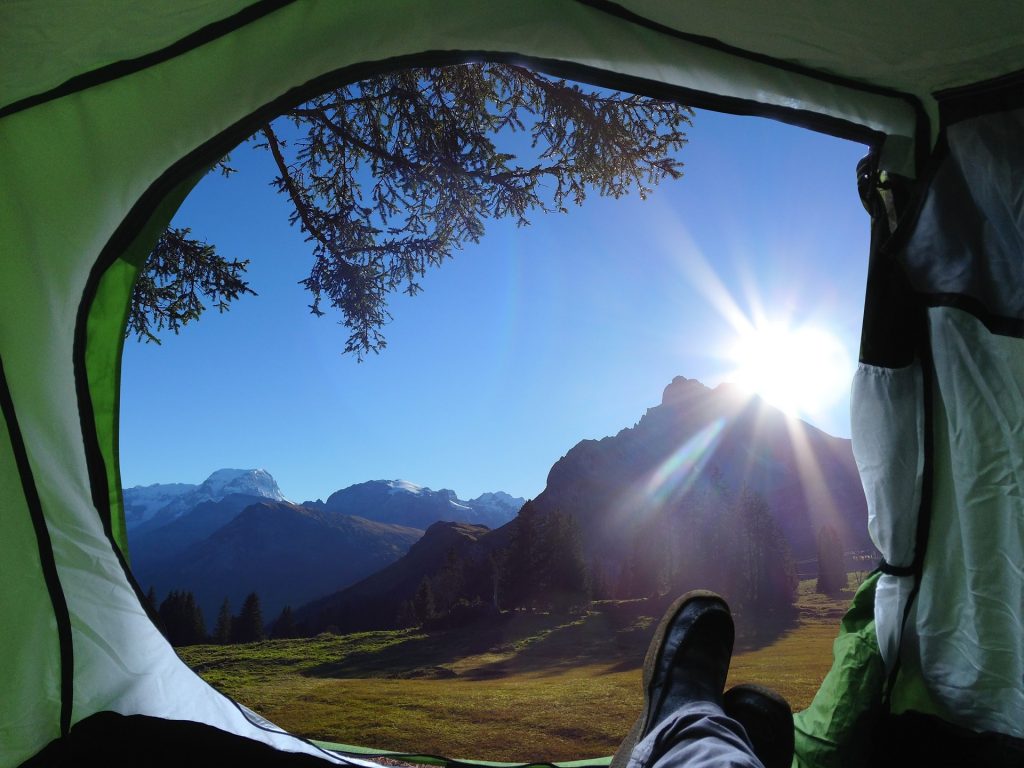 Feet extended out from a tent to mountain views