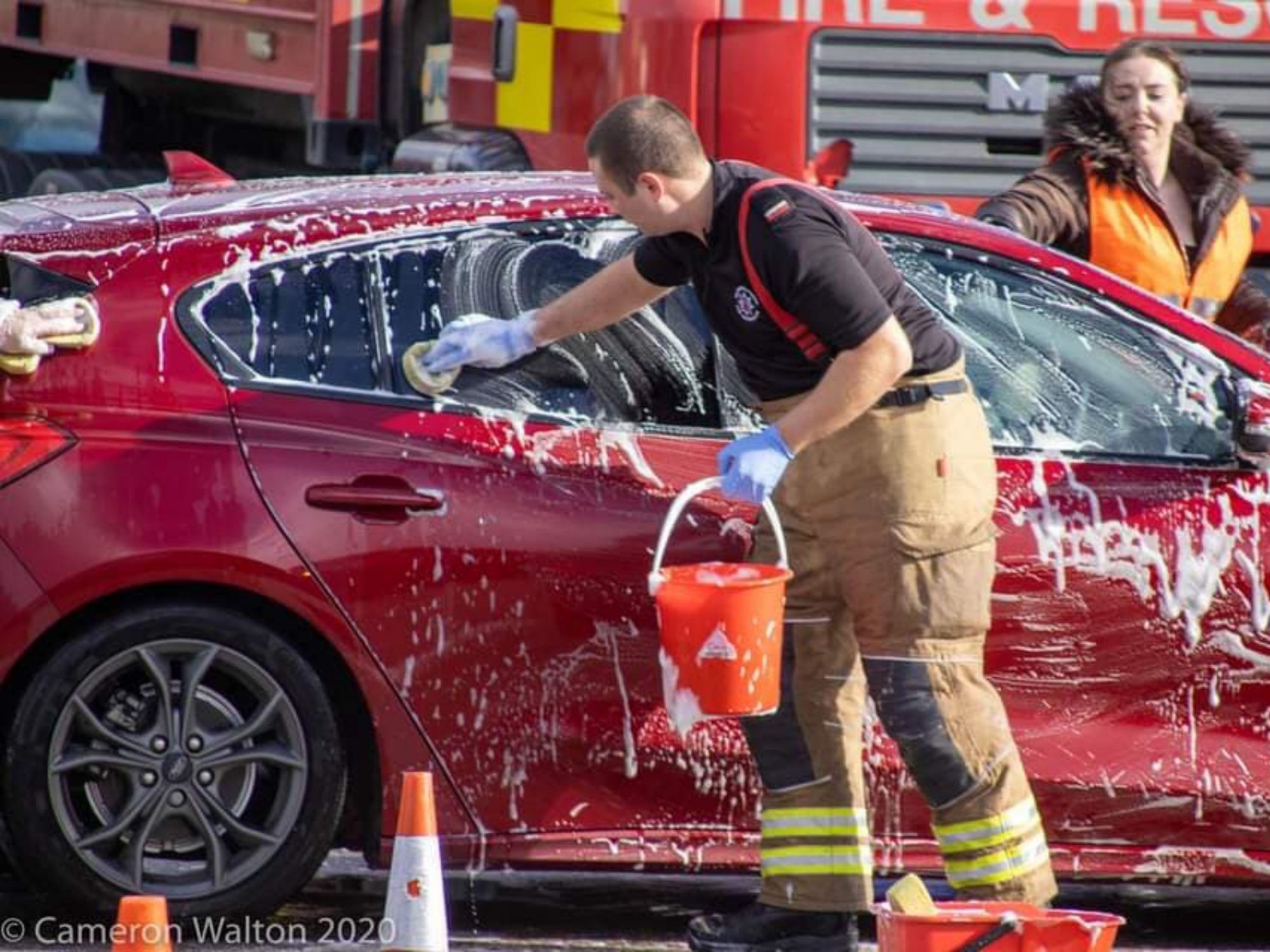 Firefighter and staff washing car for charity event