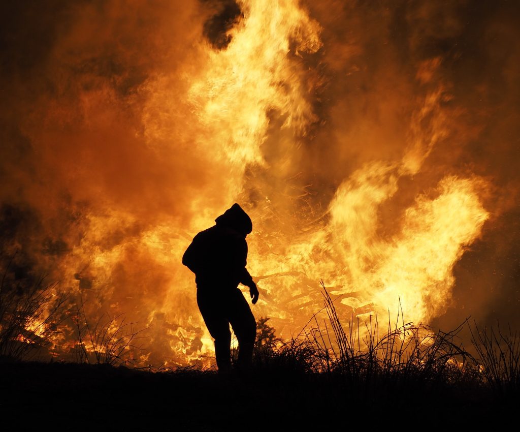 Silhouette of a person against a wildfire