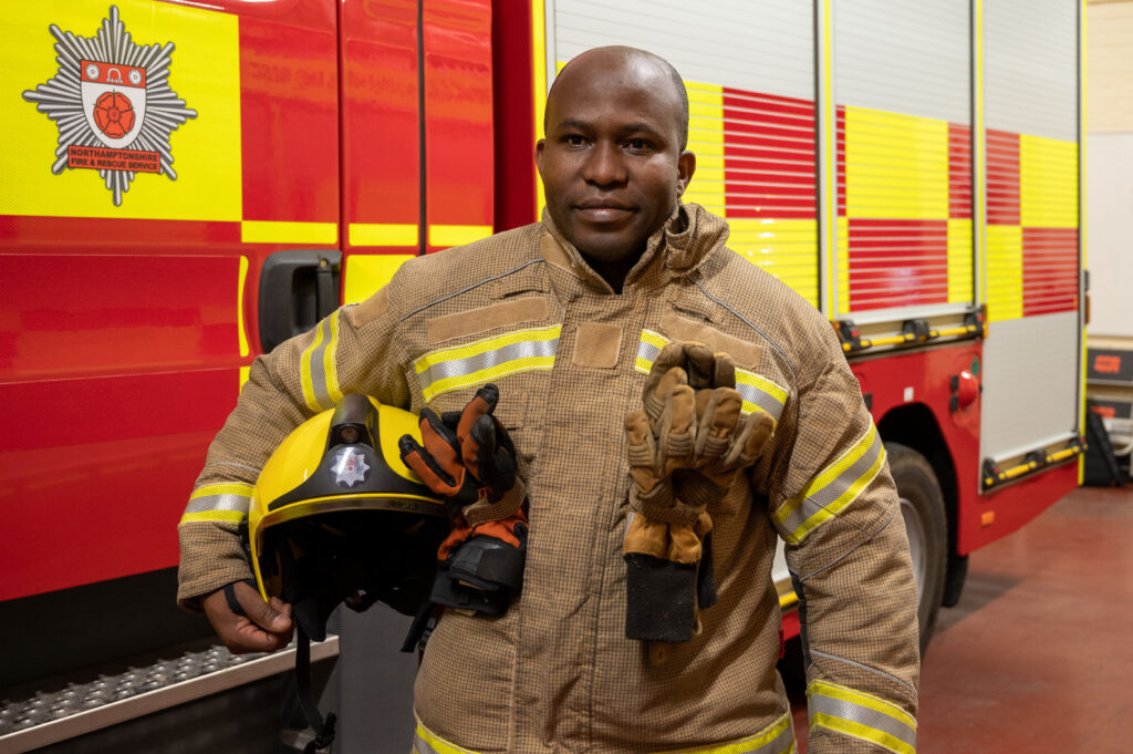 Firefighter in uniform next to fire appliance
