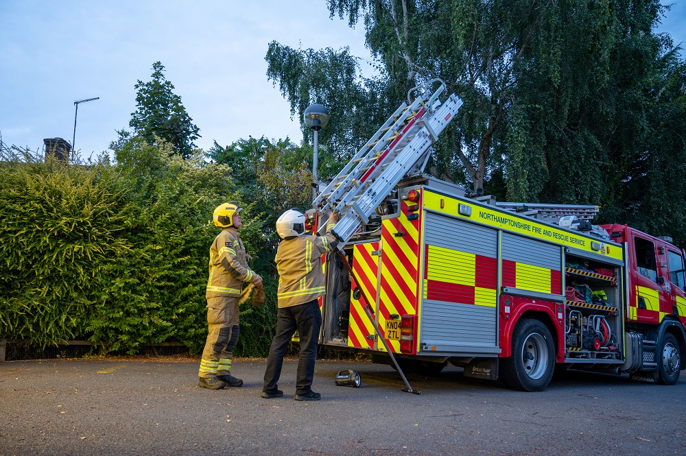 Two firefighters with ladder on fire appliance