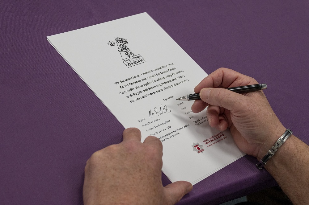 A picture showing the hand of Chief Fire Officer Mark Jones, as he signs the Armed Forces Covenant with a pen