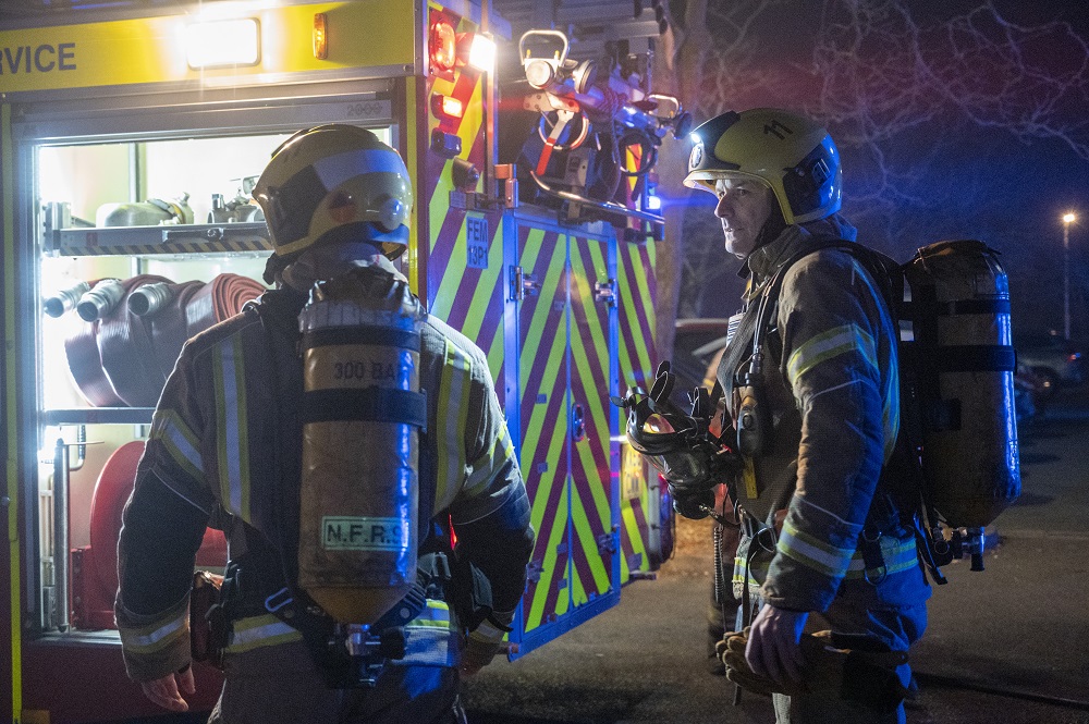 Two firefighters wearing breathing apparatus are shown taking part in Exercise Curtain Call