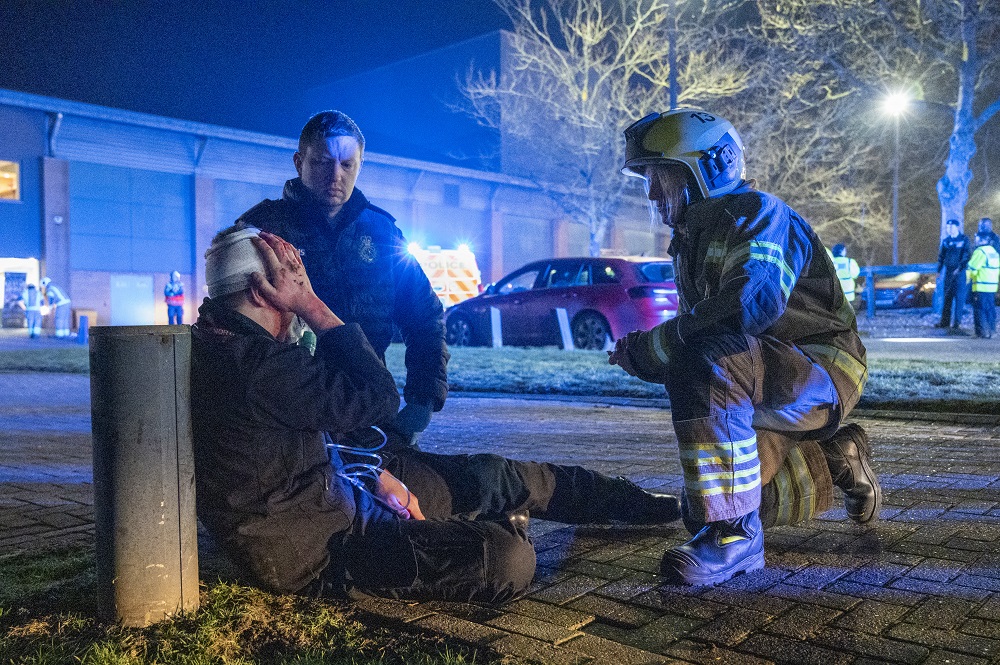 A volunteer with fake injuries, who is on the ground clutching his head, receives treatment from two workers taking part in Exercise Curtain Call