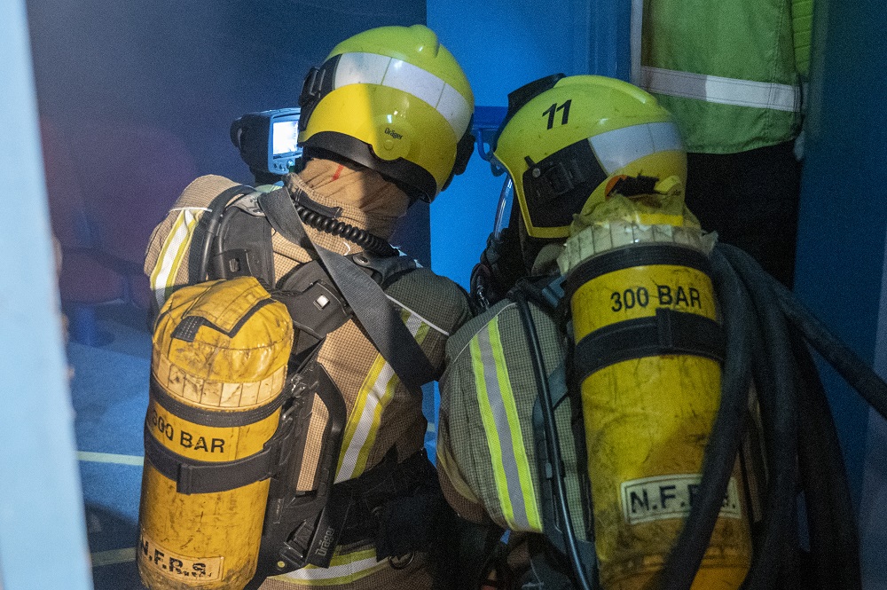 Two firefighters wearing breathing apparatus are pictured low down on the floor, ready to enter the auditorium at the Lighthouse Theatre in Kettering, where Exercise Curtain Call was taking place