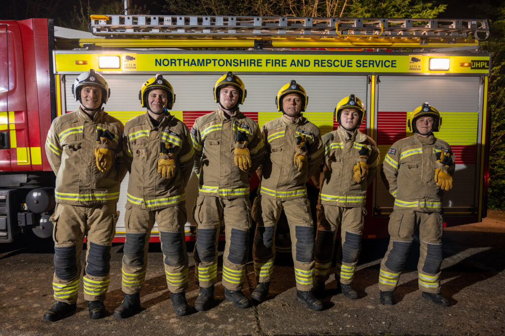Brixworth Fire crew stood with the side of their fire engine behind them 