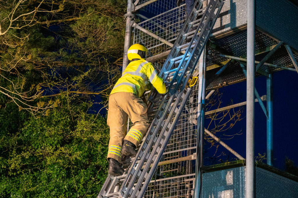 A firefighter going up a ladder