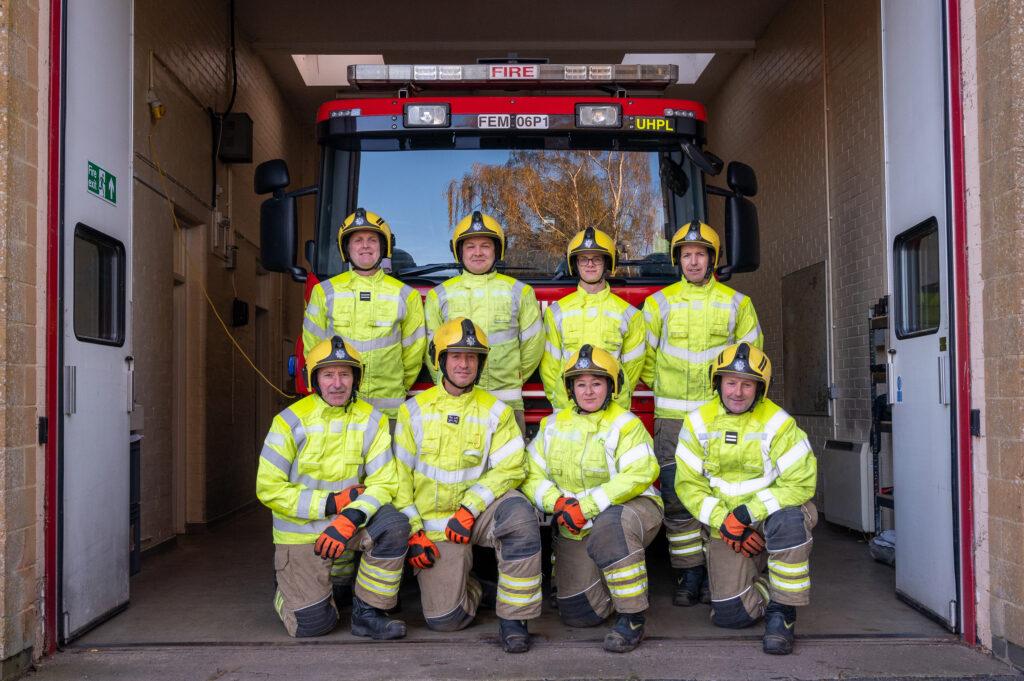 The Guilsborough On Call crew standing in two rows in front of their fire appliance 