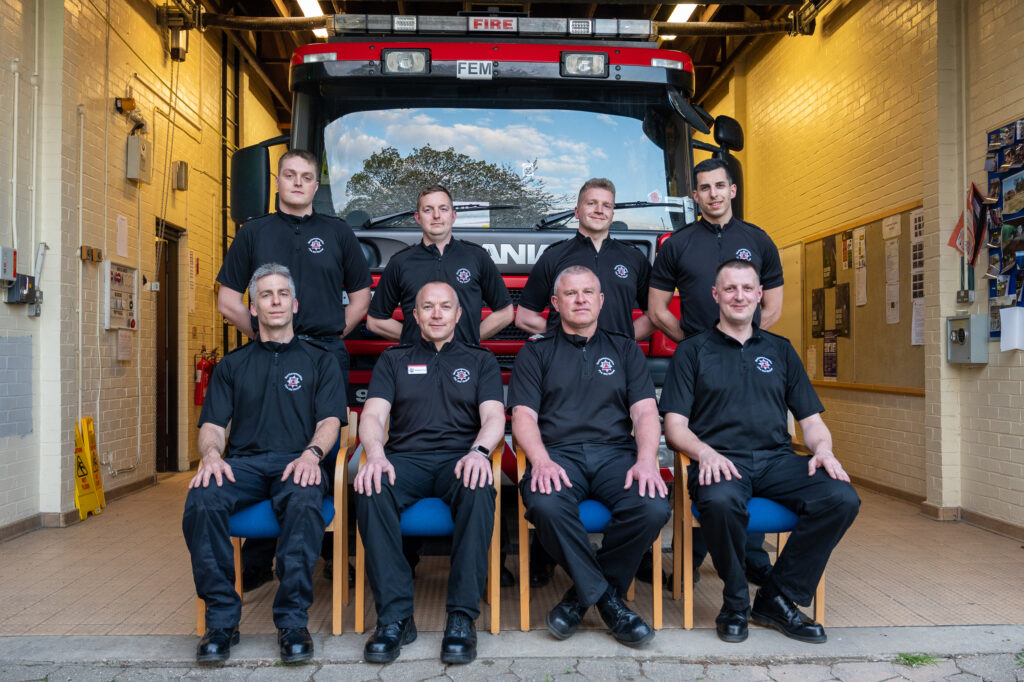 Oundle fire crew consisting of 8 firefighters stood and sat in front of their fire engine