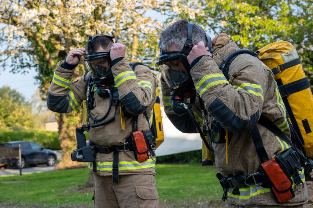 Two firefighters putting on breathing apparatus 