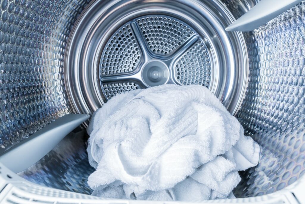 A photograph shows a white tea towel on the inside of a tumble dryer