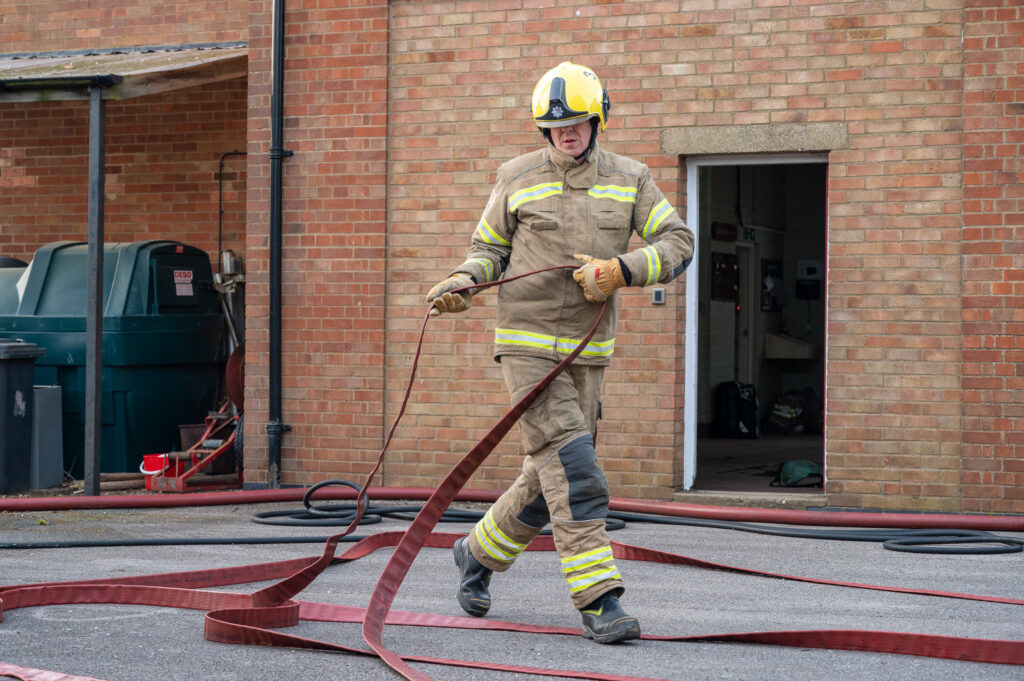 A firefighter running out some hose 