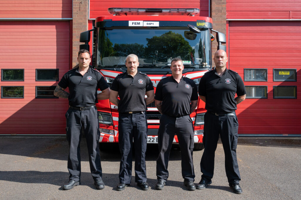Four members of the Daventry fire crew, left to right, are Duncan Timbs, Sebastien Ward, James Young and Keiran Davies. The four are shown in their black firefighter shirts in front of the Daventry fire engine.