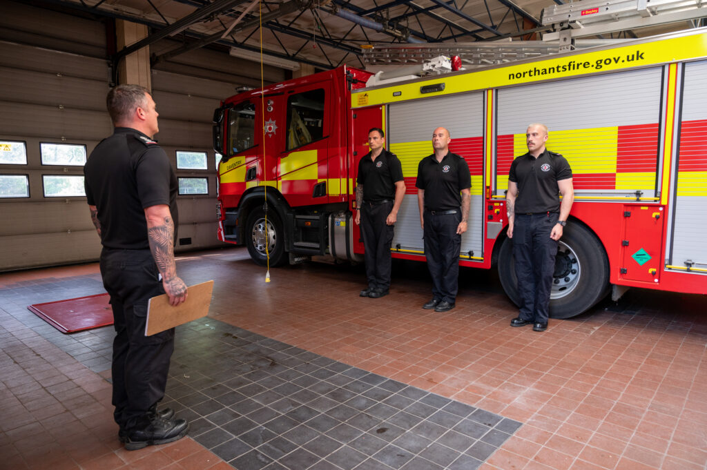 The Daventry crew report for Parade. On the left is Watch Manager Duncan Timbs. Facing him are three crew members in front of the fire engine - Sebastien Ward, James Young and Kieran Davies.