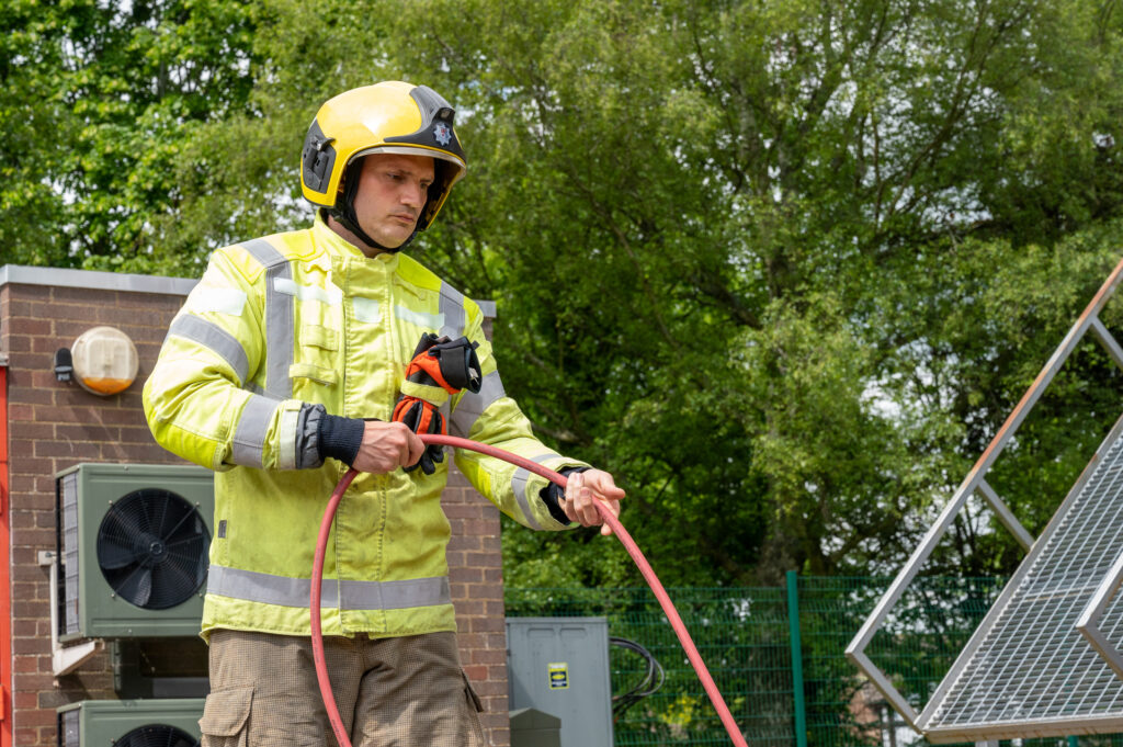 Firefighter Sebastian Ward, wearing a flourescent rescue jacket, holds a red cable during a drill that mimics the rescue of a person trapped in a car