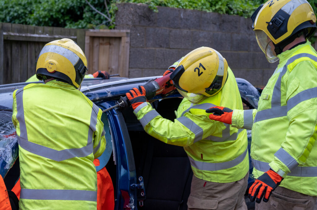 3 firefighters cutting up a car