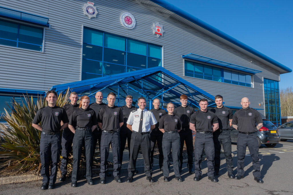 12 new firefighters dressed in their black uniform stood outside Service HQ with CFO Simon Tuhill