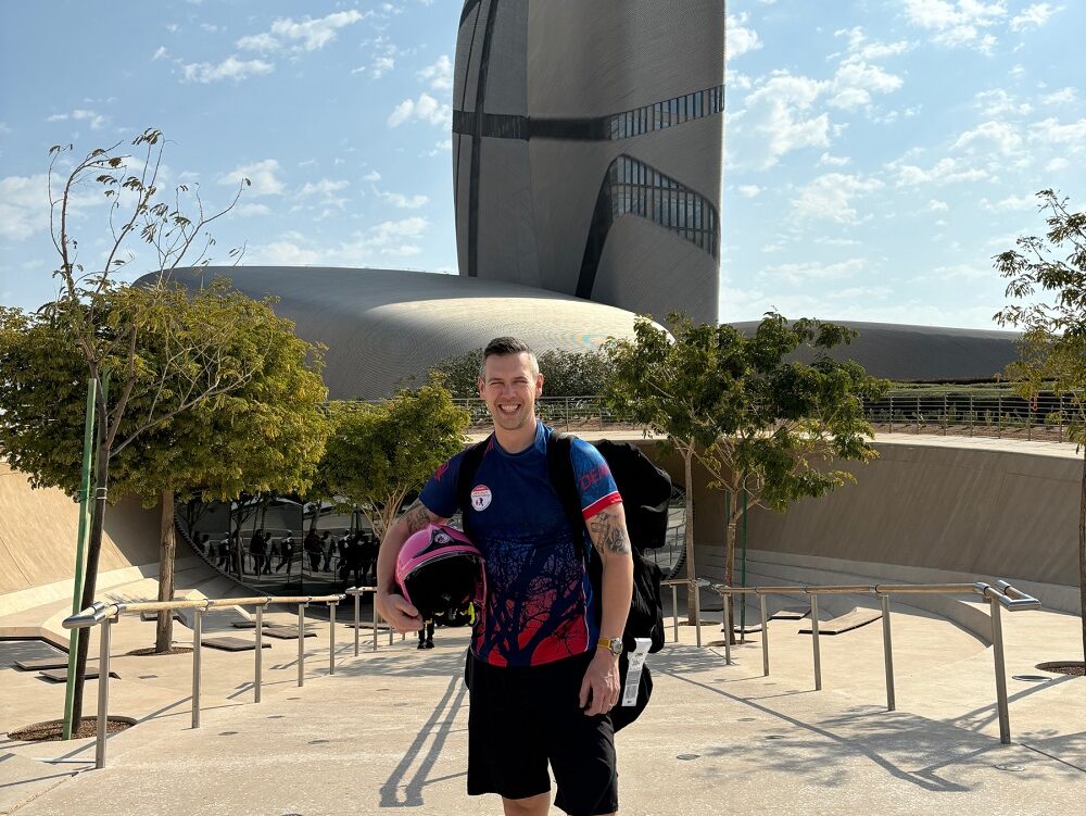 Dean Keeber stands in front of a tower in Saudi Arabia which is shown in the background