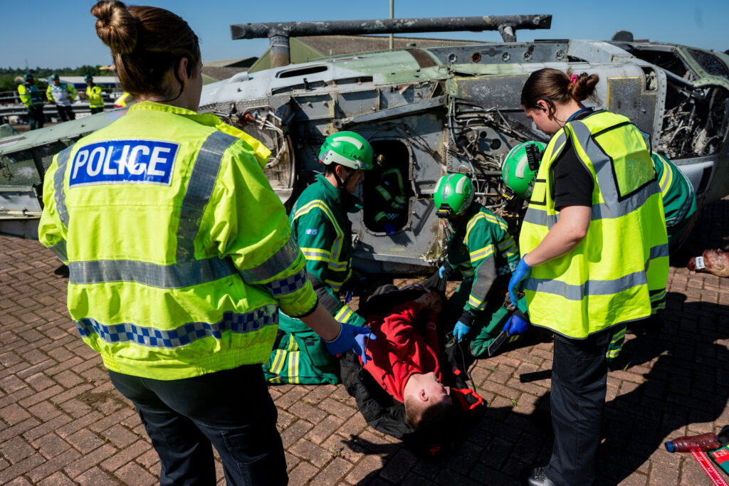 Emergency services at the scene of the mock aircraft collision earlier. Ambulance crews are pictured tending to a patient who has been recovered from a helicopter.