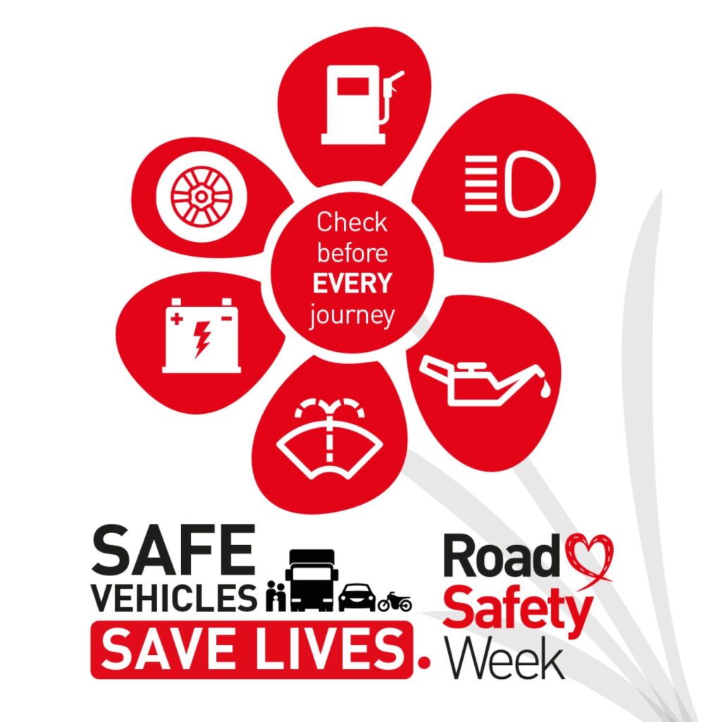 A red flower-shaped graphic with six petals, each showing a car maintenance icon: fuel pump, headlight, oil can, windscreen wiper, battery, and tire. The center circle reads “Check before EVERY journey.” Below, bold text says “SAFE VEHICLES SAVE LIVES” with silhouettes of a truck, car, motorcycle, and pedestrian. To the right, text reads “Road Safety Week” with a heart-shaped design.